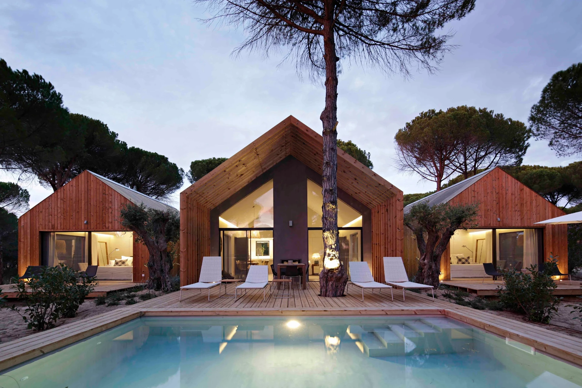 Sublime Comporta Villa K at dusk, seen across its pool through stone pines